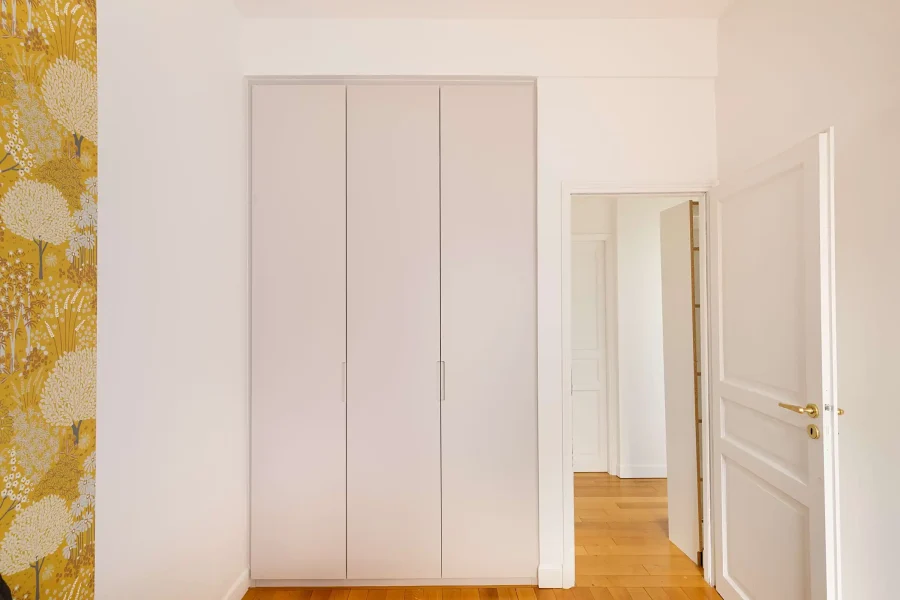 Armoire intégrée sur mesure à façade blanche épurée avec rangement toute hauteur dans une chambre