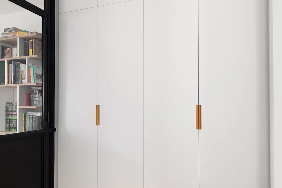 Dressing intégré dans le mur avec poignées bois naturel et façades blanches mates