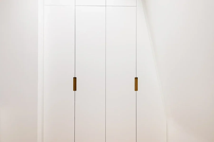 Vue d’ensemble du dressing sous comble blanc avec portes laquées et poignées bois